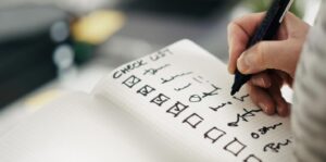 Hand checking items off a written checklist, representing the ISO 14001:2026 transition process